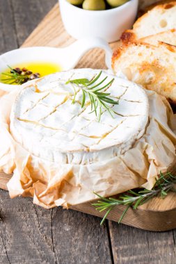 Pişmiş camembert peyniri. Taze Brie peyniri ve bir dilim fındık, tatlım, biberiye ile ahşap bir gemide, baget ekmek ızgara tost ve yaprakları. Peynir Brie türü. İtalyan, Fransız peynir.