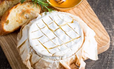 Pişmiş camembert peyniri. Taze Brie peyniri ve bir dilim fındık, tatlım, biberiye ile ahşap bir gemide, baget ekmek ızgara tost ve yaprakları. Peynir Brie türü. İtalyan, Fransız peynir.