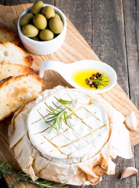 Pişmiş camembert peyniri. Taze Brie peyniri ve bir dilim fındık, tatlım, biberiye ile ahşap bir gemide, baget ekmek ızgara tost ve yaprakları. Peynir Brie türü. İtalyan, Fransız peynir.