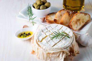 Pişmiş camembert peyniri. Taze Brie peyniri ve bir dilim fındık, tatlım, biberiye ile ahşap bir gemide, baget ekmek ızgara tost ve yaprakları. Peynir Brie türü. İtalyan, Fransız peynir.