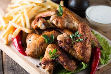 Yakın çekim fotoğraf Barbekü tavuk kanatlı patates ve bira. Barbekü soslar, ketçap, mayonez etli. Hızlı ve abur cubur kavramı. 