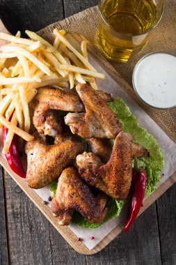 Yakın çekim fotoğraf Barbekü tavuk kanatlı patates ve bira. Barbekü soslar, ketçap, mayonez etli. Hızlı ve abur cubur kavramı. 