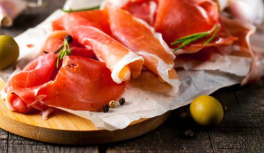 prosciutto ile karışık zeytin ve ahşap kesme tahtası üzerinde kırmızı biber ince dilim closeup