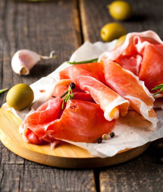 prosciutto ile karışık zeytin ve ahşap kesme tahtası üzerinde kırmızı biber ince dilim closeup
