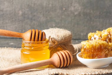 Tatlım gelen ahşap bal ayı gri rustik ahşap arka plan üzerinde bir kavanoza damlama