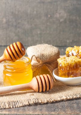 Tatlım gelen ahşap bal ayı gri rustik ahşap arka plan üzerinde bir kavanoza damlama