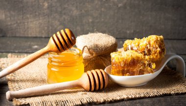 Tatlım gelen ahşap bal ayı gri rustik ahşap arka plan üzerinde bir kavanoza damlama