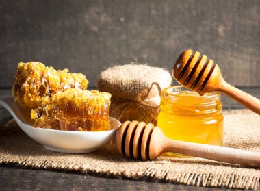 Tatlım gelen ahşap bal ayı gri rustik ahşap arka plan üzerinde bir kavanoza damlama