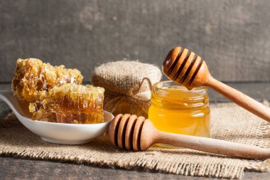 Tatlım gelen ahşap bal ayı gri rustik ahşap arka plan üzerinde bir kavanoza damlama