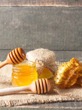 Tatlım gelen ahşap bal ayı gri rustik ahşap arka plan üzerinde bir kavanoza damlama
