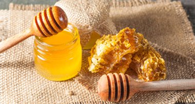 Tatlım gelen ahşap bal ayı gri rustik ahşap arka plan üzerinde bir kavanoza damlama