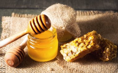 Tatlım gelen ahşap bal ayı gri rustik ahşap arka plan üzerinde bir kavanoza damlama