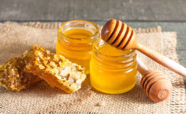 Tatlım gelen ahşap bal ayı gri rustik ahşap arka plan üzerinde bir kavanoza damlama