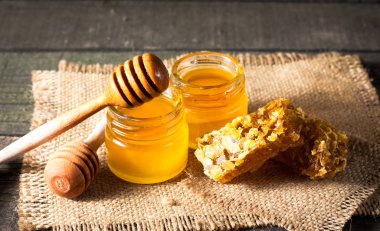 Tatlım gelen ahşap bal ayı gri rustik ahşap arka plan üzerinde bir kavanoza damlama