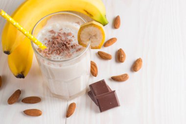 Taze yapılmış çikolata muz Smoothie ahşap bir masa üzerinde. Seçici odak. Bademli muzlu süt. Protein diyeti. Sağlıklı yiyecek ve içecek konsepti.