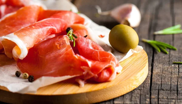prosciutto ile karışık zeytin ve ahşap kesme tahtası üzerinde kırmızı biber ince dilim closeup
