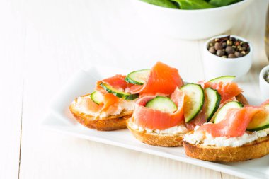 Somon, salatalık ve krem peynir bruschetta. İtalyan tapas antipasti sebzeler, otlar ve ızgara ciabatta ve baget ekmek üzerine. Sandviç.