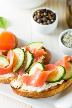 Somon, salatalık ve krem peynir bruschetta. İtalyan tapas antipasti sebzeler, otlar ve ızgara ciabatta ve baget ekmek üzerine. Sandviç.