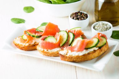 Somon, salatalık ve krem peynir bruschetta. İtalyan tapas antipasti sebzeler, otlar ve ızgara ciabatta ve baget ekmek üzerine. Sandviç.