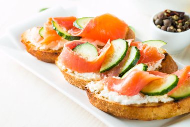 Somon, salatalık ve krem peynir bruschetta. İtalyan tapas antipasti sebzeler, otlar ve ızgara ciabatta ve baget ekmek üzerine. Sandviç.