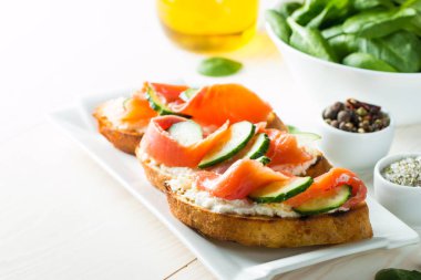 Somon, salatalık ve krem peynir bruschetta. İtalyan tapas antipasti sebzeler, otlar ve ızgara ciabatta ve baget ekmek üzerine. Sandviç.