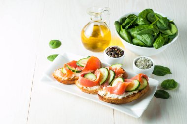 Somon, salatalık ve krem peynir bruschetta. İtalyan tapas antipasti sebzeler, otlar ve ızgara ciabatta ve baget ekmek üzerine. Sandviç.