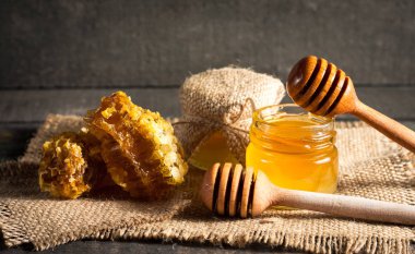 Tatlım gelen ahşap bal ayı gri rustik ahşap arka plan üzerinde bir kavanoza damlama