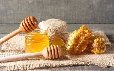 Tatlım gelen ahşap bal ayı gri rustik ahşap arka plan üzerinde bir kavanoza damlama