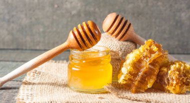 Tatlım gelen ahşap bal ayı gri rustik ahşap arka plan üzerinde bir kavanoza damlama