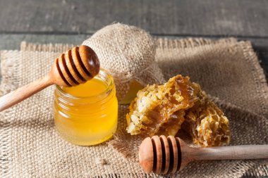 Tatlım gelen ahşap bal ayı gri rustik ahşap arka plan üzerinde bir kavanoza damlama