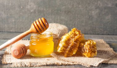 Tatlım gelen ahşap bal ayı gri rustik ahşap arka plan üzerinde bir kavanoza damlama