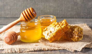 Tatlım gelen ahşap bal ayı gri rustik ahşap arka plan üzerinde bir kavanoza damlama