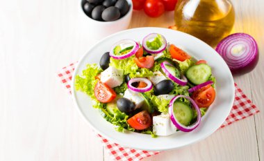 Kiraz domates, ruccola, roka, beyaz peynir, zeytin, salatalık, soğan ve baharat taze Yunan salatası yaptı. Sezar salatası ahşap arka plan üzerinde beyaz bir kase. Sağlıklı organik beslenme gıda kavramı.