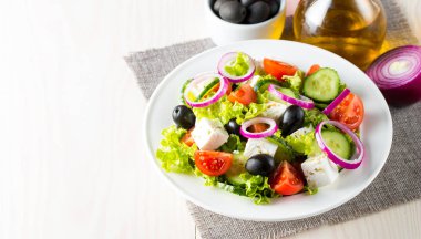 Kiraz domates, ruccola, roka, beyaz peynir, zeytin, salatalık, soğan ve baharat taze Yunan salatası yaptı. Sezar salatası ahşap arka plan üzerinde beyaz bir kase. Sağlıklı organik beslenme gıda kavramı.