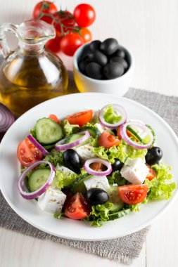 Kiraz domates, ruccola, roka, beyaz peynir, zeytin, salatalık, soğan ve baharat taze Yunan salatası yaptı. Sezar salatası ahşap arka plan üzerinde beyaz bir kase. Sağlıklı organik beslenme gıda kavramı.