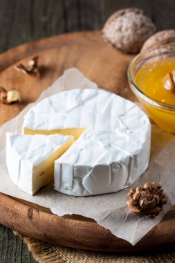 Brie peyniri. Camembert peyniri. Taze Brie peyniri ve tahtadan bir dilim fındık, bal ve yaprakla. İtalyan, Fransız peyniri.