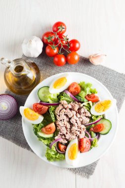 Domates, roka, ton balığı, yumurta, roka, kraker ve baharattan yapılmış taze balık salatası. Tahta arka planda beyaz bir kasede Sezar salatası.