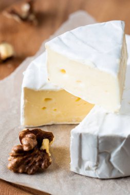 Brie peyniri. Camembert peyniri. Taze Brie peyniri ve tahtadan bir dilim fındık, bal ve yaprakla. İtalyan, Fransız peyniri.