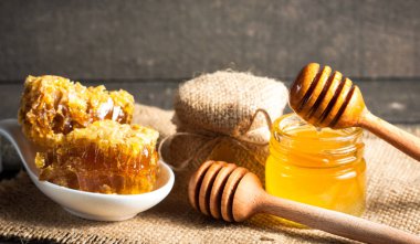 Tatlım gelen ahşap bal ayı gri rustik ahşap arka plan üzerinde bir kavanoza damlama