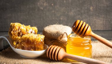 Tatlım gelen ahşap bal ayı gri rustik ahşap arka plan üzerinde bir kavanoza damlama