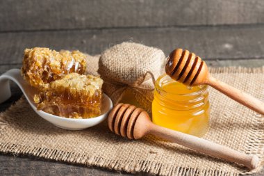 Tatlım gelen ahşap bal ayı gri rustik ahşap arka plan üzerinde bir kavanoza damlama