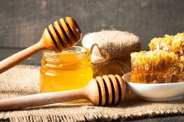 Tatlım gelen ahşap bal ayı gri rustik ahşap arka plan üzerinde bir kavanoza damlama