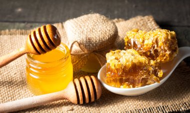 Tatlım gelen ahşap bal ayı gri rustik ahşap arka plan üzerinde bir kavanoza damlama