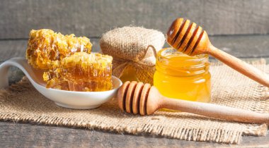 Tatlım gelen ahşap bal ayı gri rustik ahşap arka plan üzerinde bir kavanoza damlama