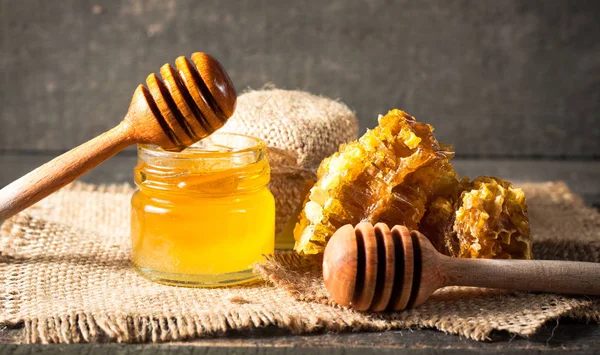 从木蜂蜜北斗在一个罐子里木灰色乡村背景上滴下来的蜂蜜 — 图库照片