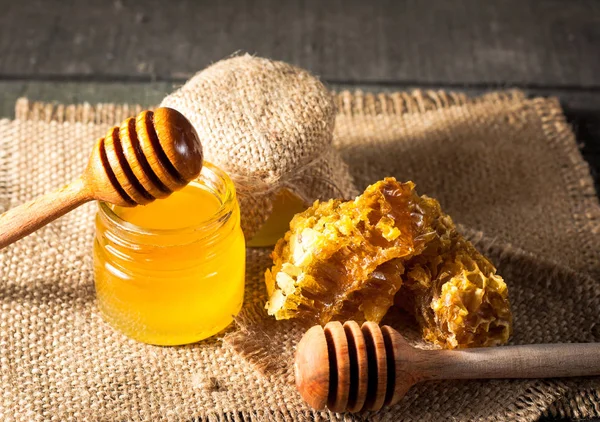 从木蜂蜜北斗在一个罐子里木灰色乡村背景上滴下来的蜂蜜 — 图库照片