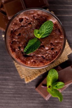 Çikolata, kahve, süt, muz sallamak ahşap arka plan üzerinde. Nane ile güler yüzlü. Milkshake. Protein diyeti. Sağlıklı yiyecek ve içecek konsepti.