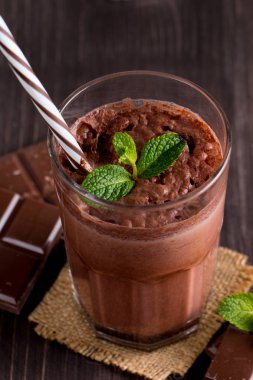 Çikolata, kahve, süt, muz sallamak ahşap arka plan üzerinde. Nane ile güler yüzlü. Milkshake. Protein diyeti. Sağlıklı yiyecek ve içecek konsepti.