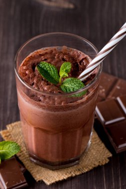 Çikolata, kahve, süt, muz sallamak ahşap arka plan üzerinde. Nane ile güler yüzlü. Milkshake. Protein diyeti. Sağlıklı yiyecek ve içecek konsepti.