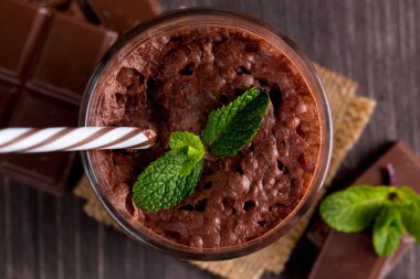 Çikolata, kahve, süt, muz sallamak ahşap arka plan üzerinde. Nane ile güler yüzlü. Milkshake. Protein diyeti. Sağlıklı yiyecek ve içecek konsepti.